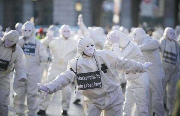 Manifestantes con disfraces y máscaras blancas actúan durante una protesta contra las restricciones por el COVID-19 en la Heldenplatz en Viena, Austria, el 16 de enero de 2021. (Foto de Georg Hochmuth / APA / AFP a través de Getty Images)