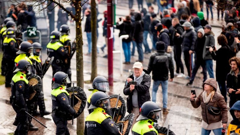 La policía antidisturbios holandesa se para cerca de activistas antigubernamentales mientras denuncian las restricciones en curso relacionadas con la pandemia de la enfermedad del COVID-19, entre otros problemas, en Museumplein, Ámsterdam, Países Bajos, el 17 de enero de 2021. (Foto de Robin Van Lonkhuijsen / ANP / AFP a través de Getty Images)