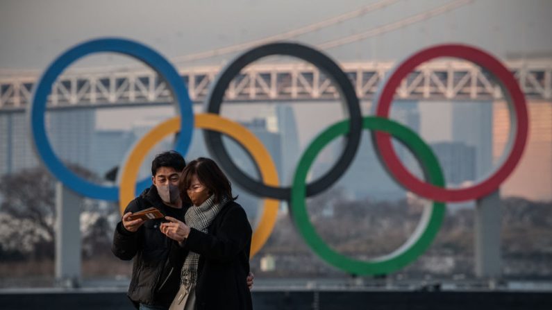 Una pareja revisa su celular después de tomarse un selfie juntos frente a los Anillos Olímpicos el 22 de enero de 2021 en Tokio, Japón. (Carl Court / Getty Images)