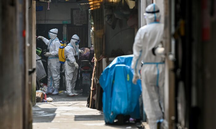 Trabajadores sanitarios con equipo de protección rocían desinfectante en una zona bloqueada en el distrito Huangpu de Shanghai el 27 de enero de 2021, luego de que los residentes fueran evacuados tras la detección de algunos casos de COVID-19 en el vecindario. (STR/AFP vía Getty Images)