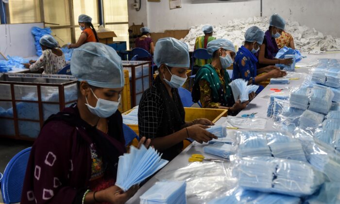 Empleados empaquetan mascarillas quirúrgicas en una fábrica cerca de Changodar, a unos 20 km de Ahmedabad, India, el 8 de noviembre de 2020. (SAM PANTHAKY/AFP vía Getty Images)