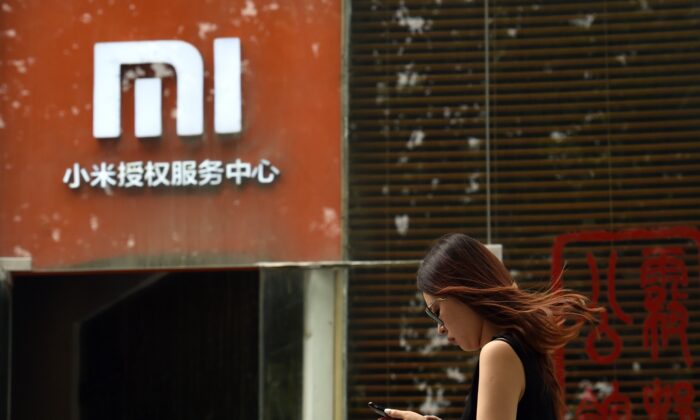 Una mujer pasa por delante de un logotipo de Xiaomi fuera de un centro de servicio de Xiaomi en Beijing el 5 de agosto de 2015. (Greg Baker/AFP vía Getty Images)