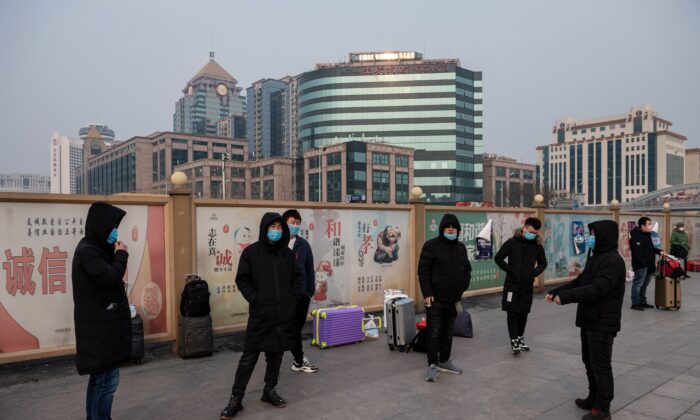 Personas con mascarillas esperan junto a sus maletas en la estación de tren de Beijing el 27 de enero de 2020. (Nicolas Asfouri/AFP vía Getty Images)
