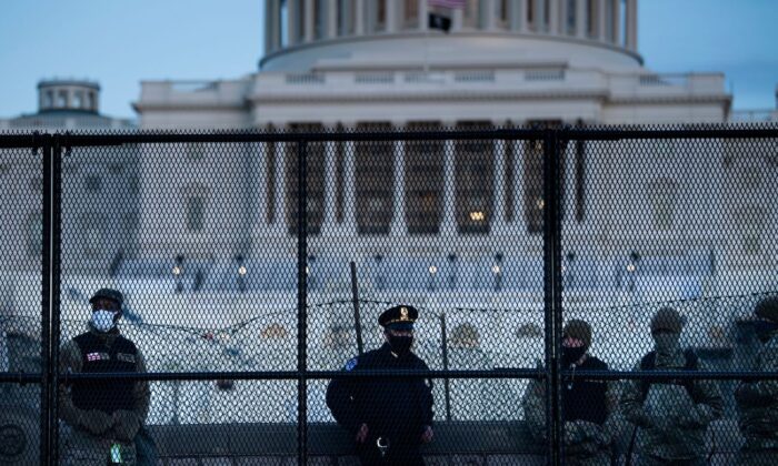 Un agente de la Policía del Capitolio hace guardia con soldados de la Guardia Nacional detrás de una valla de control de multitudes que rodea el Capitolio un día después de que un grupo irrumpiera en el Capitolio de EE. UU. en Washington, el 7 de enero de 2021. (Brendan Smialowski/AFP vía Getty Images)