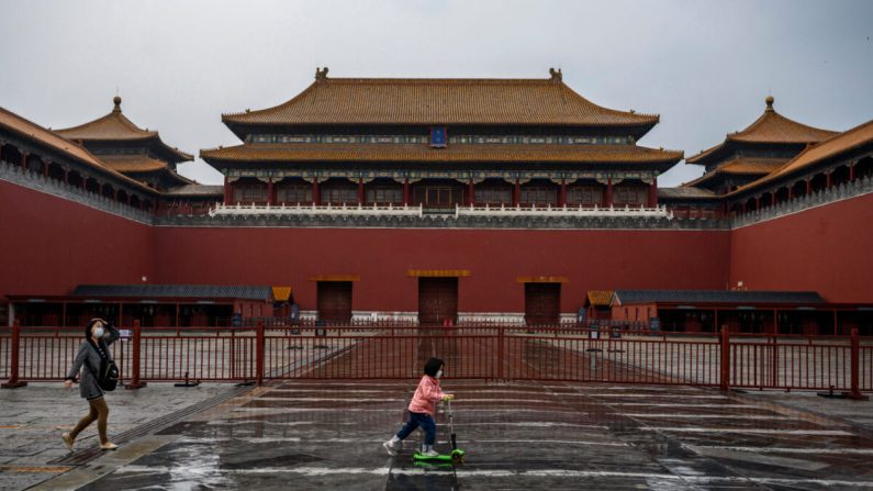 Una niña china usa una mascarilla protectora mientras conduce su scooter frente a la puerta de la Ciudad Prohibida, que permanece cerrada a los visitantes, en Beijing, China, el 19 de abril de 2020. (Kevin Frayer/Getty Images)