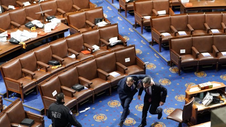 Los miembros del Congreso corren para cubrirse mientras los manifestantes tratan de entrar en la Cámara de Representantes durante una sesión conjunta del Congreso en Washington el 6 de enero de 2021. (Drew Angerer/Getty Images)