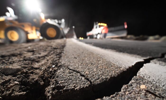 Trabajadores de la autopista reparan un agujero que se abrió en la carretera como resultado del terremoto del 5 de julio de 2019, en Ridgecrest, California, a unas 150 millas (241 km) al norte de Los Ángeles, a primera hora de la mañana del 6 de julio de 2019. (Robyn Beck/AFP vía Getty Images)