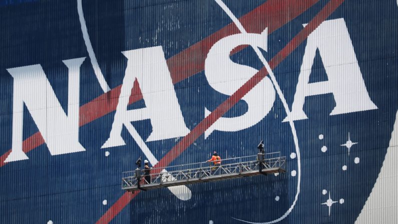Trabajadores retocan la pintura del logo de la NASA en el Edificio de Ensamblaje de Vehículos antes de la llegada de los astronautas de la NASA Bob Behnken y Doug Hurley al Centro Espacial Kennedy en Cabo Cañaveral, Florida, el 20 de mayo de 2020. (Joe Raedle/Getty Images)

