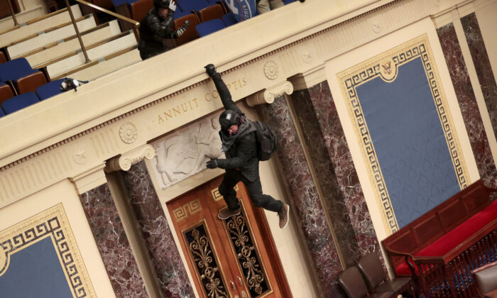 Se ve a un manifestante colgado del balcón de la Cámara del Senado en Washington el 6 de enero de 2021. (Win McNamee/Getty Images)