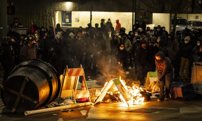 Un manifestante agrega combustible a una barricada en llamas, en una intersección en el centro de Tacoma, Washington, el 24 de enero de 2021. (David Ryder/Getty Images)