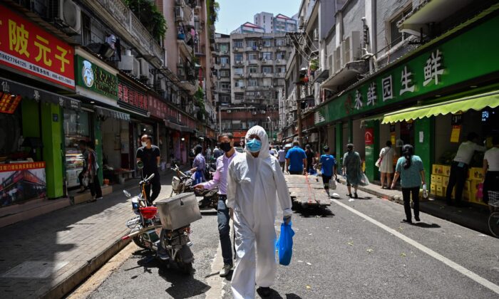 Un hombre vestido con equipo de protección pasa frente a las tiendas de Wuhan, provincia de Hubei, China, el 18 de mayo de 2020. (Hector Retamal/AFP a través de Getty Images)