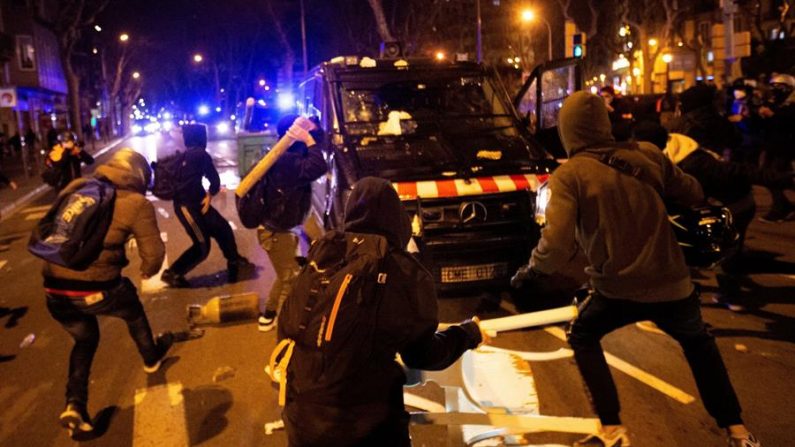Varios manifestantes lanzan objetos a un vehículo de los cuerpos antidisturbios tras la manifestación de protesta por la detención del rapero Pablo Hasel en España. EFE/Enric Fontcuberta
