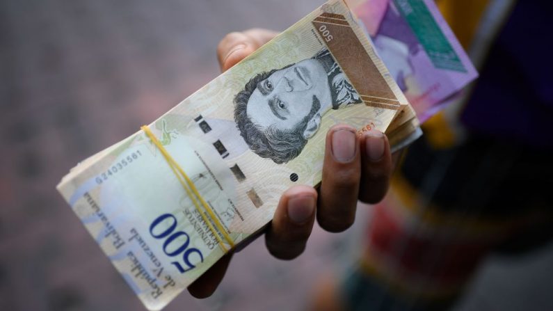 Un hombre sostiene billetes de Bolívar en una calle de Caracas, Venezuela, el 13 de junio de 2019. (Federico Parra / AFP via Getty Images)