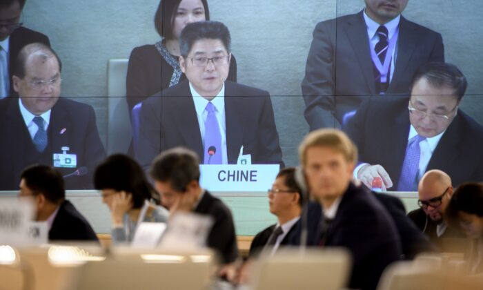 El viceministro de Asuntos Exteriores de China, Le Yucheng (C), aparece en una pantalla gigante de televisión pronunciando un discurso ante el Consejo de Derechos Humanos de las Naciones Unidas (ONU) en Ginebra, el 6 de noviembre de 2018. (Fabrice Coffrini/AFP vía Getty Images)