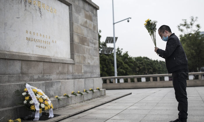 Un residente ofrenda flores a los mártires que murieron en la lucha contra el brote del virus del PCCh y a los compatriotas que murieron de la enfermedad en Wuhan, China, el 4 de abril de 2020. (Getty Images)