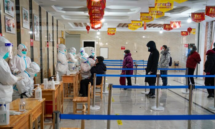 Un trabajador médico toma una muestra de un hisopo de un hombre mientras la gente hace fila para realizarse pruebas del coronavirus Covid-19 en un edificio de oficinas en Harbin, en la provincia de Heilongjiang, noreste de China, el 14 de enero de 2021, después de que la provincia declarara un "estado de emergencia" conforme aumentan las cifras diarias de Covid-19. (STR/AFP a través de Getty Images)