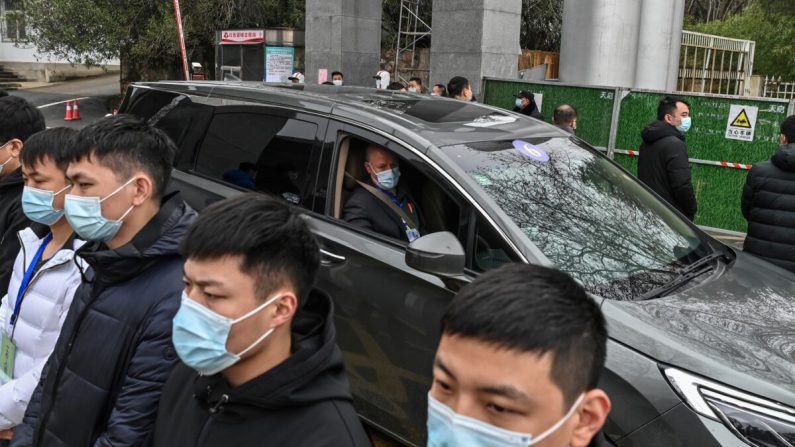 Miembros del equipo de la Organización Mundial de la Salud (OMS) que investiga los orígenes del COVID-19, abandonan el centro provincial de Hubei para el control y la prevención de enfermedades, mientras un grupo de guardias impiden que las personas se acerquen, en Wuhan, China, el 1 de febrero de 2021. (HECTOR RETAMAL/AFP a través de Getty Images)