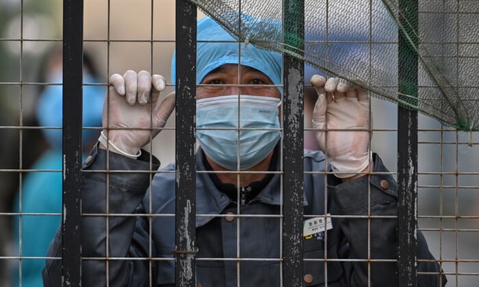Un trabajador con mascarilla mira desde la entrada de un hospital hacia el Centro de Control y Prevención de Enfermedades de Wuhan, en la provincia central china de Hubei, el 1 de febrero de 2021. (HECTOR RETAMAL/AFP vía Getty Images)