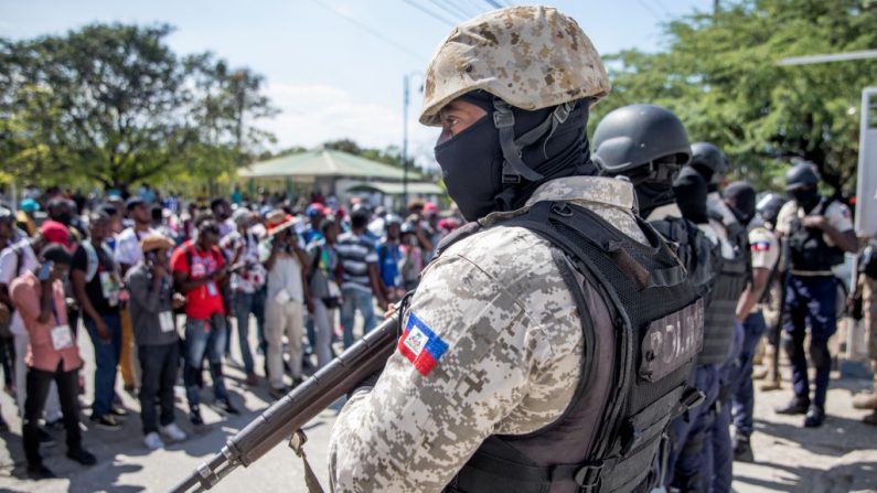 Periodistas se enfrentan a policías armados cuando se reúnen frente a la Dirección Departamental de Policía para presentar una denuncia luego de que fueron atacados con gases lacrimógenos mientras cubrían una protesta contra el presidente haitiano en Puerto Príncipe, el 10 de febrero de 2021. (Foto de Valerie Baeriswyl / AFP a través de Getty Images)