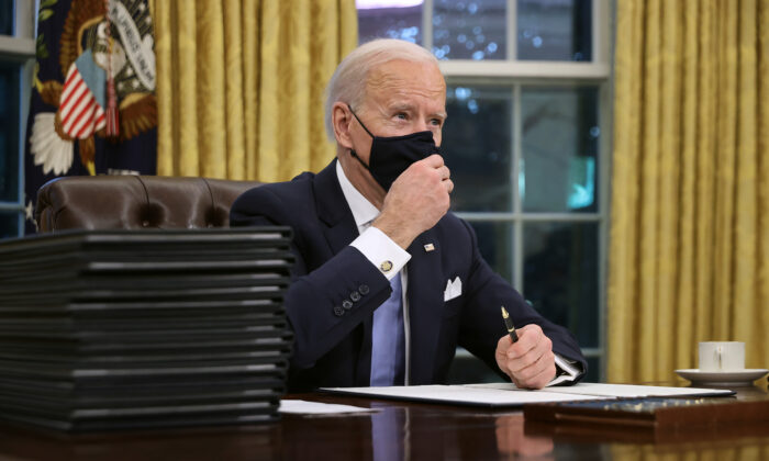 El presidente Joe Biden se prepara para firmar una serie de órdenes ejecutivas en el Escritorio Resolute del Despacho Oval en Washington, horas después de su toma de posesión el 20 de enero de 2021. (Chip Somodevilla/Getty Images)