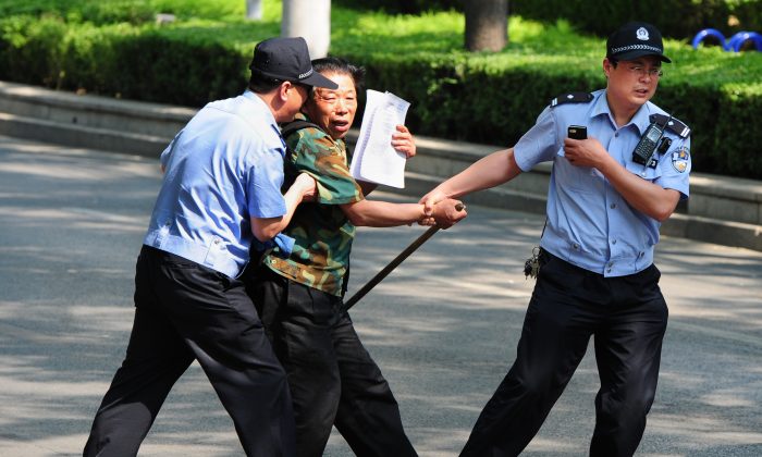 Un peticionario es detenido por la policía a las puertas del Hospital Chaoyang, en Beijing, el 8 de mayo de 2012, donde un grupo de personas protesta por temas de salud y por el acaparamiento de tierras. (MARK RALSTON/AFP/GettyImages)