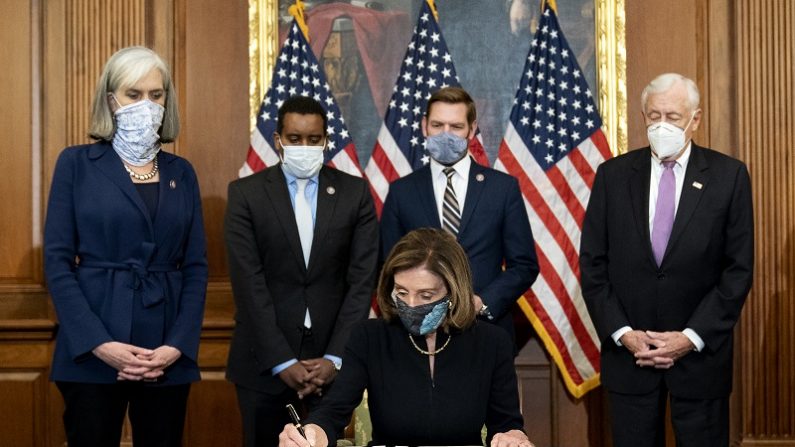 La presidenta de la Cámara de Representantes, Nancy Pelosi (D-Calif.), firma un artículo de impeachment contra el expresidente Donald Trump en el Capitolio de Estados Unidos en Washington el 13 de enero de 2021. (Stefani Reynolds/Getty Images)
