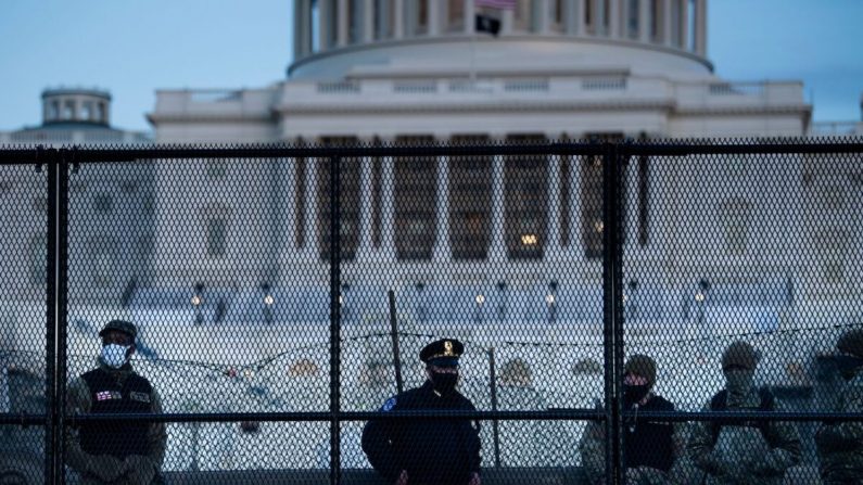 Un oficial de policía del Capitolio se encuentra con miembros de la Guardia Nacional detrás de una valla de control de multitudes que rodea Capitol Hill un día después de que un grupo irrumpió en el Capitolio de los EE. UU. en Washington, el 7 de enero de 2021. (Brendan Smialowski/AFP a través de Getty Images)