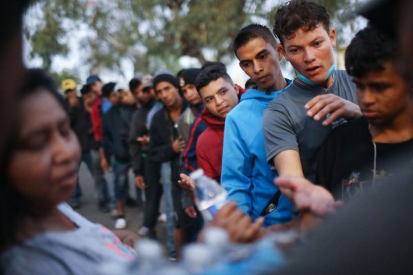 Los migrantes esperan recibir comida y agua donadas afuera de un refugio temporal establecido para miembros de la caravana de migrantes, en Tijuana, México, el 28 de noviembre de 2018. (Mario Tama/Getty Images)