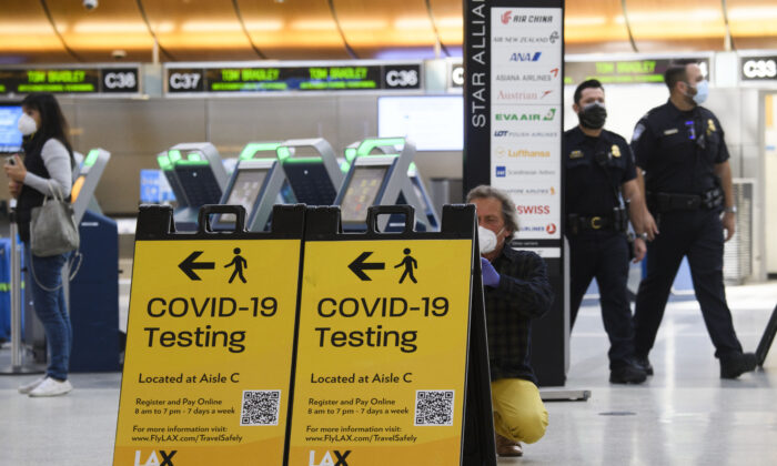 Un viajero toma una foto de un cartel de pruebas de COVID-19 en la terminal internacional Tom Bradley, en Los Ángeles, California, el 4 de febrero de 2021. (Patrick T. Fallon/AFP vía Getty Images)