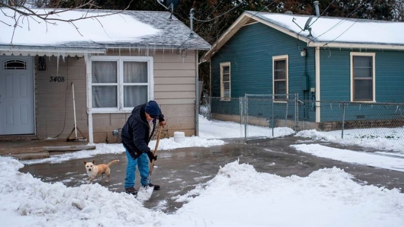 Un residente de Waco, Texas, limpia la nieve de su camino de entrada junto a su perro el 17 de febrero de 2021, ya que las severas condiciones climáticas invernales de los últimos días han obligado a cerrar carreteras y cortes de energía en el estado. (Matthew Busch / AFP vía Getty Images)