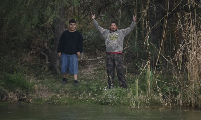 Presuntos traficantes de personas, también conocidos como 'coyotes', hacen un gesto mientras se paran en el lado mexicano del Río Grande, cerca de EE.UU., en la ciudad fronteriza de Roma, el 28 de marzo de 2021. (Ed Jones/AFP a través de Getty Images).