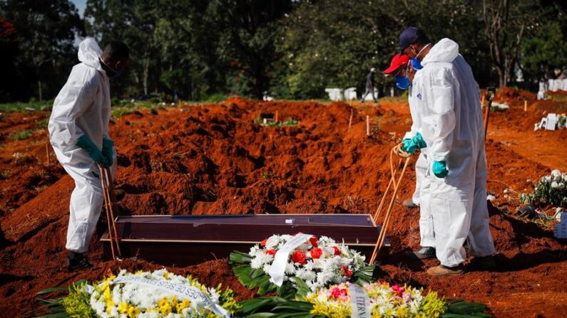Unos trabajadores colocan un ataúd dentro de una tumba en el cementerio Vila Formosa el 24 de marzo de 2021, en Sao Paulo (Brasil). EFE/ Fernando Bizerra
