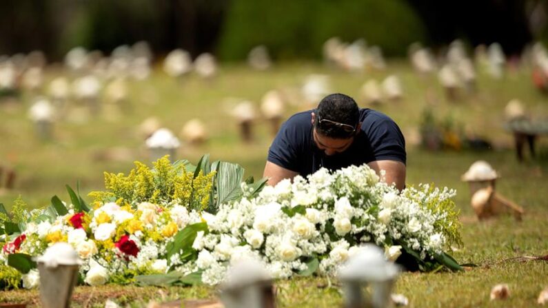 Un hombre visita una tumba en el cementerio Campo de Esperanza el 23 de marzo de 2021, en Brasilia (Brasil). EFE/Joédson Alves
