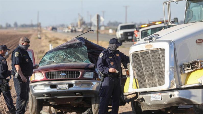 Funcionarios policiales inspeccionan los restos de una camioneta que chocó con un semirremolque en la ruta estatal 115, en Holtville, California, el 02 de marzo de 2021. (EFE/EPA/Sandy Huffaker)