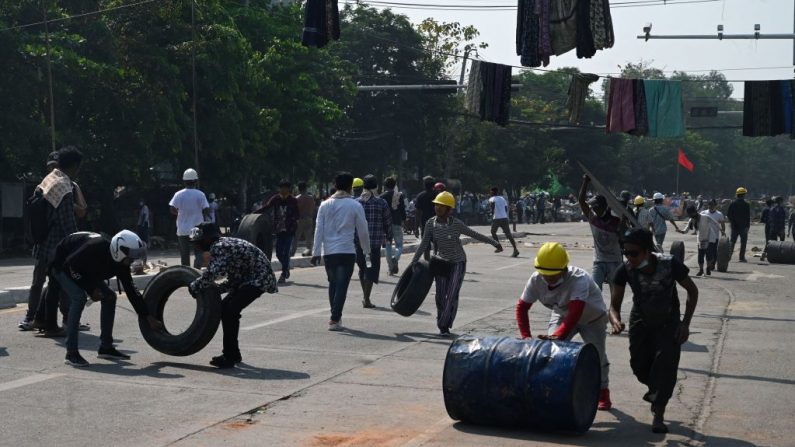 Los manifestantes llevan un neumático mientras otro rueda un barril para construir una barricada mientras participan en una manifestación contra el golpe militar en Rangún, Birmania, el 11 de marzo de 2021. (STR / AFP a través de Getty Images)