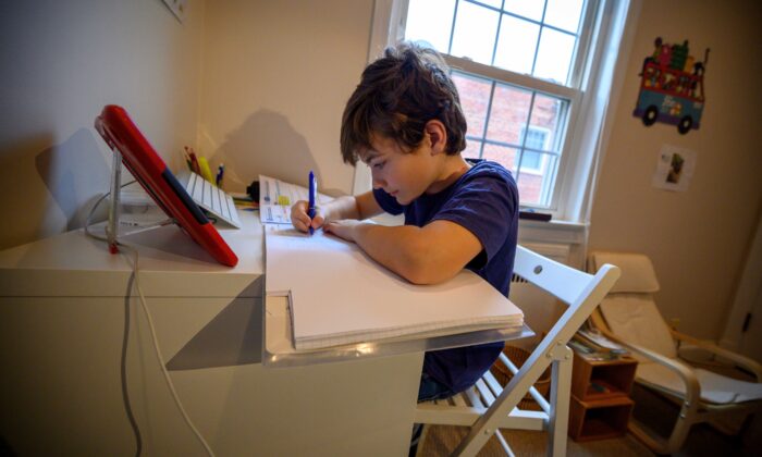 Colin, de 10 años, cuya escuela cerró después del brote del virus del PCCh, hace ejercicios escolares en su casa en Washington, el 20 de marzo de 2020. (Eric Baradat/AFP a través de Getty Images)