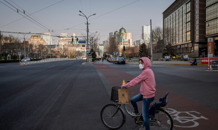 Una mujer con su bicicleta en una calle casi vacía de Beijing el 22 de marzo de 2020. (Nicolas Asfouri/AFP vía Getty Images)