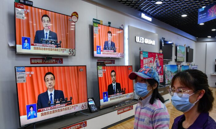La gente pasa por delante de los televisores que emiten la cobertura en directo del CCTV. (AFP vía Getty Images)