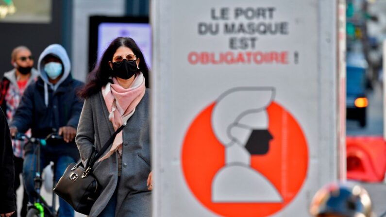 Una mujer usa mascarilla mientras pasa junto a un letrero que dice "usar una máscara es obligatorio'' en una calle de Bruselas, Bélgica, el 6 de noviembre de 2020. (John Thys / AFP vía Getty Images)