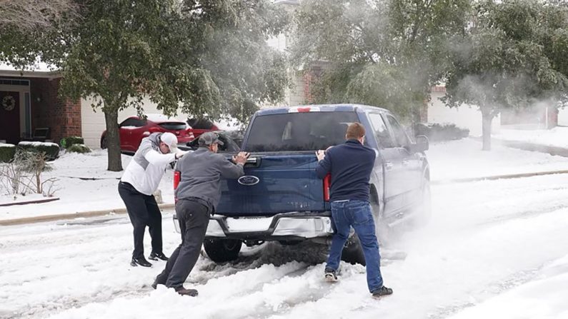 Residentes ayudan a un conductor de una camioneta a salir del hielo en la carretera en Round Rock, Texas, el 17 de febrero de 2021, después de una tormenta de invierno. (SUZANNE CORDEIRO/AFP vía Getty Images)