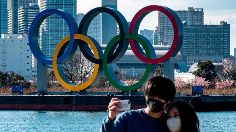 Una pareja posa para fotos frente a los anillos olímpicos que se exhiben en el paseo marítimo de Odaiba en Tokio, Japón, el 24 de febrero de 2021. (Philip Fong / AFP vía Getty Images)