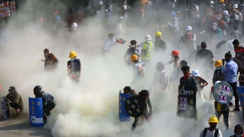 Los manifestantes reaccionan después de que la policía lanzara gases lacrimógenos durante una manifestación contra el golpe militar en la ciudad noroccidental de Kale, Birmania, el 2 de marzo de 2021. (STR / AFP vía Getty Images)