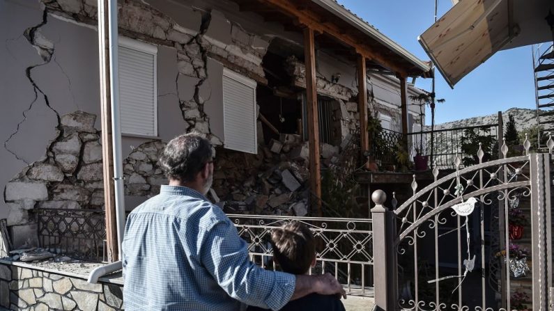 Un padre y un hijo observan una casa dañada en el pueblo de Damasi, cerca de la ciudad de Tyrnavos, después de que un fuerte terremoto de magnitud 6.3 azotara la región central griega de Tesalia el 3 de marzo de 2021. (Sakis Mitrolidis / AFP a través de Getty Images)
