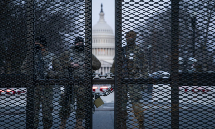 Antes del amanecer, los miembros de la Guardia Nacional permanecen detrás de una valla de alambre de púas que rodea el Capitolio en Washington, el 4 de marzo de 2021. (Sarah Silbiger/Getty Images)