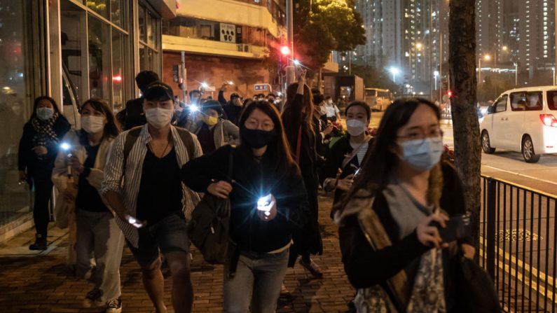 Manifestantes agitan las luces de sus teléfonos celulares cuando ven un vehículo del Departamento de Servicios Correccionales (CSD) frente a los Tribunales de Magistrados de West Kowloon, la demostración ocurrió luego del cuarto día de una audiencia de fianza para 47 activistas de la oposición acusados de violar la ley de seguridad nacional de la ciudad, el 4 de marzo de 2021, en Hong Kong. (Anthony Kwan/Getty Images)