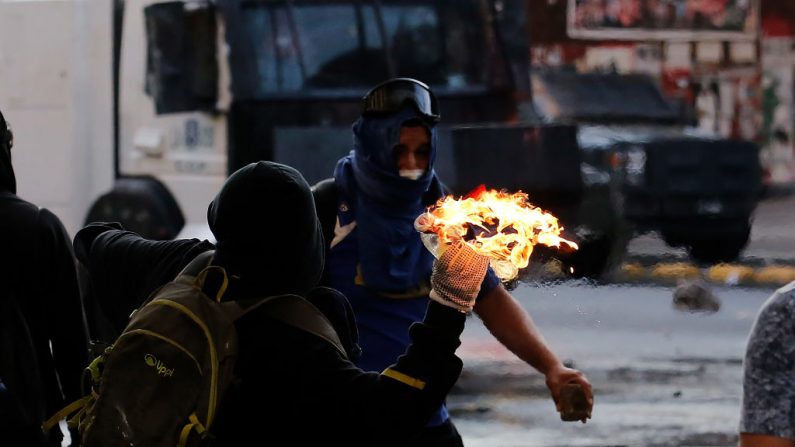 Un hombre enmascarado lanza un cóctel Molotov a la policía durante una protesta contra el presidente Sebastián Piñera el 5 de marzo de 2021 en Santiago, Chile. (Marcelo Hernandez / Getty Images)