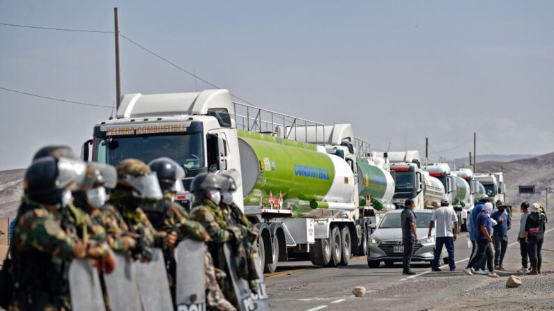 La policía antidisturbios monta guardia mientras camiones bloquean la Highwa Panamericana Sur para protestar contra el aumento del precio del combustible en las afueras de Arequipa, Perú, el 16 de marzo de 2021. (Diego Ramos / AFP a través de Getty Images)