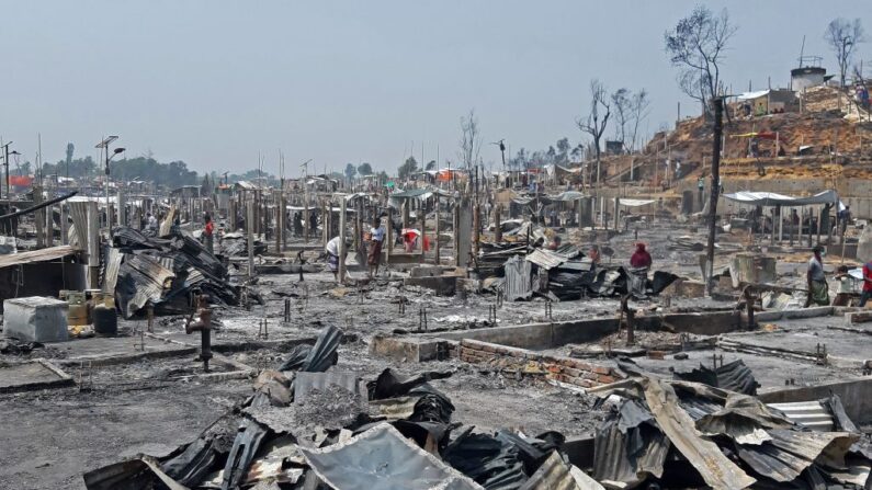 Se ve a personas entre los escombros en un campo de refugiados rohinyá en Ukhia (Bangladesh) el 23 de marzo de 2021 después de que un gran incendio obligó a unas 50,000 personas a evacuarse. (AFP vía Getty Images)