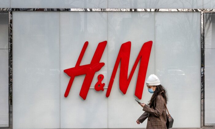 Una mujer camina junto a una tienda de la marca de ropa H&M en una zona comercial el 25 de marzo de 2021 en Beijing, China. (Kevin Frayer/Getty Images)