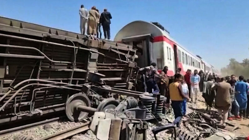 Esta captura de pantalla proporcionada por AFPTV muestra a personas reunidas alrededor de los restos de dos trenes que chocaron en el distrito de Tahta de la provincia de Sohag, a unos 460 kilómetros (285 millas) al sur de la capital egipcia, El Cairo, matando al menos a 32 personas e hiriendo a decenas de otras el 26 de marzo de 2021. (AFP vía Getty Images)